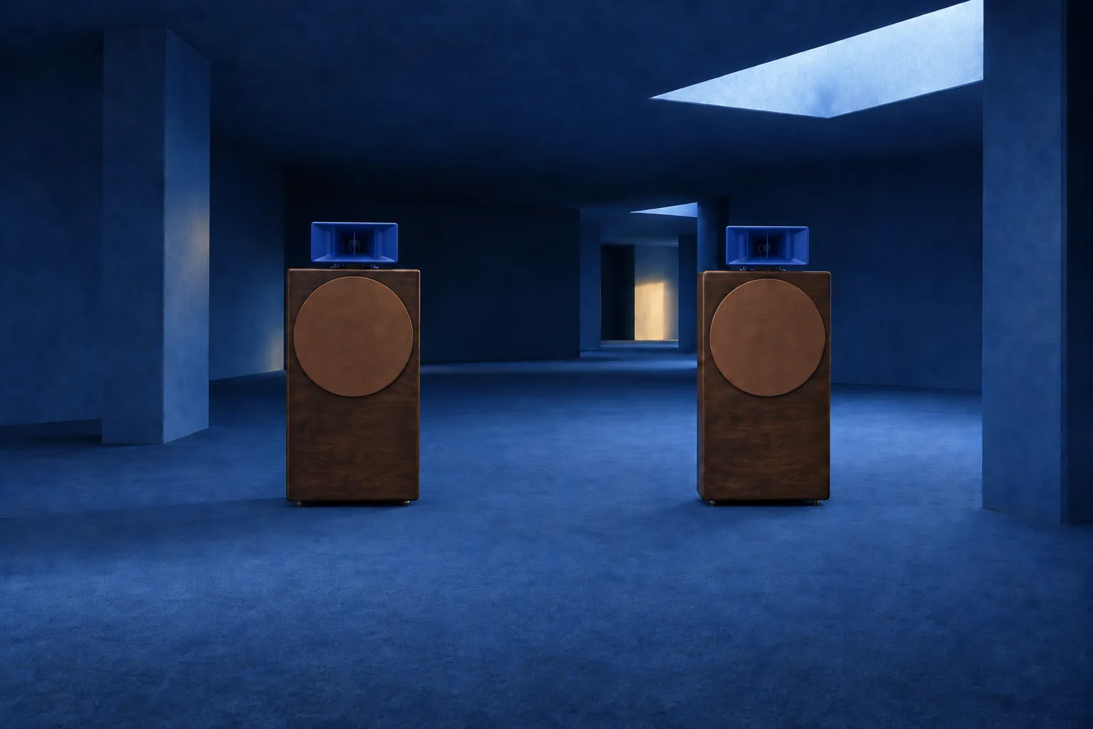 A pair of dark walnut speakers with cobalt blue horns in a blue minimalist interior lit by a skylight